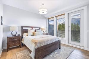 Un dormitorio con una cama grande y una ventana. en Tranquil Tamarack at Tamarack Lodge, en Canmore