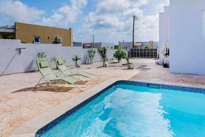 two chairs and a swimming pool on a patio at 1apt Cozy Stay Near Beach & Airport in Parkietenbos