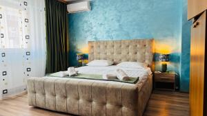 een slaapkamer met een groot bed met een blauwe muur bij SHoliday 1 Bedroom Balcony &Free Parking in Timişoara