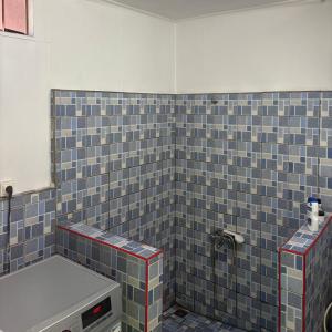 a bathroom with a blue tiled wall with a toilet at Faatiarau Bed in Fare