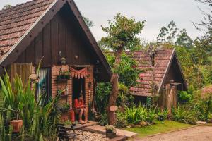 a person sitting in the doorway of a small house at Hospedagem EXCALIBUR in Visconde De Maua