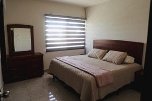 Un dormitorio con una cama y un espejo y una ventana. en Casa amplia, 3 recámaras, patio y estacionamiento, en Linares