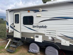 a silver and blue trailer parked in a field at Comfortable Guest RV With EV charger Semi Rural Area in Bodfish