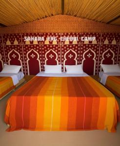 a room with two beds with a colorful bedspread at Sahara Erg Chebbi Camp in Merzouga +62 photos