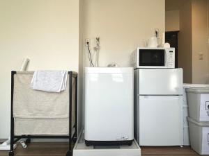 eine Küche mit zwei weißen Kühlschränken und einer Mikrowelle in der Unterkunft トライアングル若宮201 trianglewakamiya in Tokio