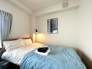 ein Hotelzimmer mit einem Bett, auf dem eine Tasche liegt in der Unterkunft トライアングル若宮201 trianglewakamiya in Tokio