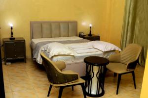 une chambre avec un lit avec deux chaises et une table dans l'établissement James Apartments, à Djouba