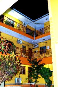un bâtiment jaune avec des balcons, des tables et des arbres dans l'établissement James Apartments, à Djouba