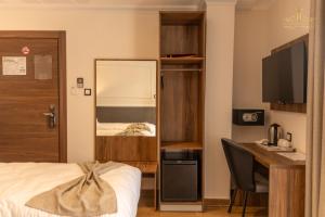 a bedroom with a bed and a desk and a mirror at Lounis Hôtel by Atlantis in Oran