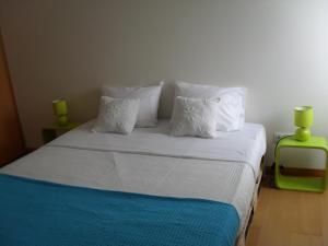 a bedroom with a bed with white sheets and pillows at 106 Green North in Ribeira Grande