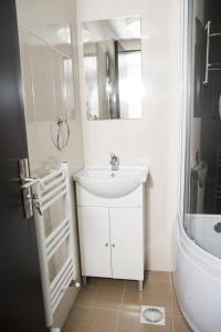 a white bathroom with a sink and a bath tub at Hostel Karisma in Bacău