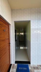 a hallway in a building with a door and a tile wall at Pousada Amorim in Frecheirinha