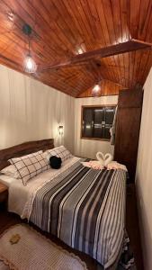a bedroom with a bed in a room with wooden ceilings at Chalé Aconchego em Campos in Campos do Jordão