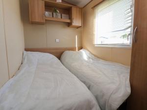 two beds in a small room with a window at The Pad in Prestatyn