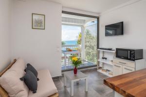 a living room with a couch and a tv and a window at Balcon des alizés pieds dans l'eau in Le Gosier +17 photos