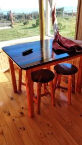 a wooden table with two stools in front of a window at Cabañas Edith in Hualaihué