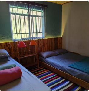 a bedroom with two beds and a window and a rug at Recanto da paz in Monte Verde