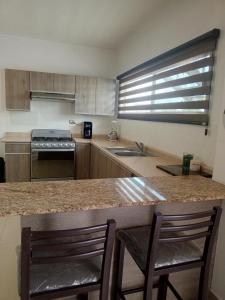 a kitchen with two chairs sitting at a counter at Departamento familiar único! BIENVENIDOS! in Torreón