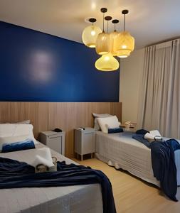 a bedroom with two beds and a blue wall at Apartamento charmoso em Santos ao lado da praia in Santos