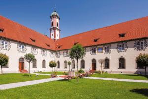 ein großes Gebäude mit rotem Dach und einem Uhrturm in der Unterkunft KurOase im Kloster in Bad Wörishofen