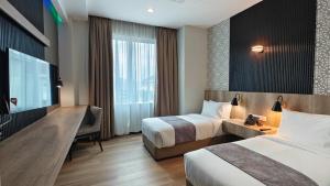 a hotel room with two beds and a television at Hotel Seri Warisan in Taiping