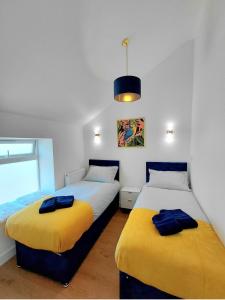 zwei Betten mit gelben und blauen Decken in einem Zimmer in der Unterkunft Blue Door Apartments in Dover