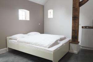 a white bed in a room with two windows at Het Centrum in Norg