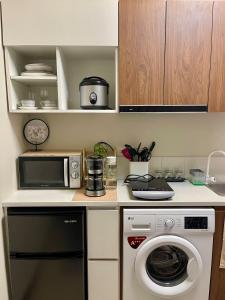 a kitchen with a washing machine and a microwave at Minimalist Studio-Type Condo Unit at Saekyung Marigondon in Suba