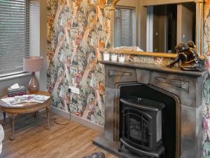 a living room with a fireplace and a mirror at Dovecote Cottage in Downham Market