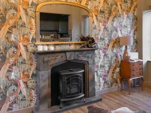 a living room with a fireplace and a mirror at Dovecote Cottage in Downham Market