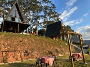 una casa su una collina con tavolo e sedie di Village dos Alpes - Chalés na Montanha Teresópolis a Teresópolis