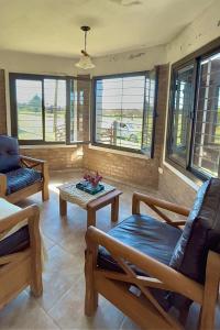 a living room with chairs and a table and windows at Cabaña El Balcón in La Estancia