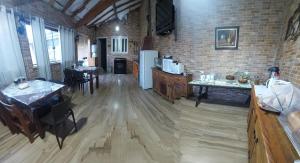 a kitchen with wooden floors and a brick wall at SUITES E QUARTOS CASA PAPAI NOEL in Campos do Jordão