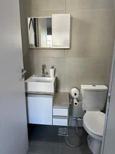 a bathroom with a toilet and a sink and a mirror at Loft Noruega 32 AC Garagem Privativa in Jaguarão