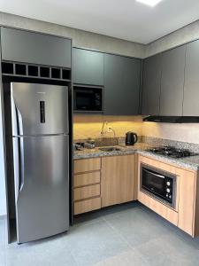 a kitchen with a stainless steel refrigerator and wooden cabinets at Loft Noruega 32 AC Garagem Privativa in Jaguarão