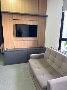 a living room with a couch and a flat screen tv at Loft Noruega 32 AC Garagem Privativa in Jaguarão +6 photos