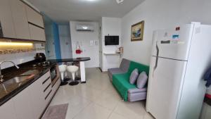 a kitchen with a couch and a white refrigerator at Caioba com excelente localização in Matinhos