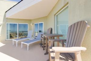 a balcony with chairs and a table and windows at 3BR Luxury Penthouse Panoramic Views in St Pete Beach