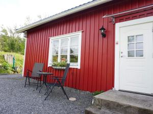 a red building with two chairs and a table in front of it at 6 person holiday home in LYSEKIL in Torgestad