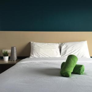 um bicho de peluche verde sentado em cima de uma cama em Huahin Terminal em Hua Hin