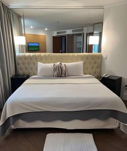 ein Schlafzimmer mit einem großen Bett und einem großen Spiegel in der Unterkunft Aparthotel Av Ibirapuera Moema Congonhas in São Paulo