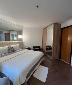 ein Hotelzimmer mit einem großen Bett und einem Spiegel in der Unterkunft Aparthotel Av Ibirapuera Moema Congonhas in São Paulo