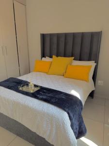 a bed with a blue blanket and yellow pillows at Charlsi luxury apartment 2 in Midrand +8 photos