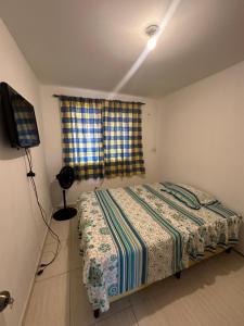 a small bedroom with a bed and a television at Habitacion amoblada frente al 99 de brisas del golf arraijan in ArraijÃ¡n
