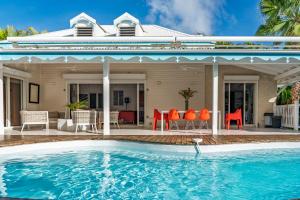 une maison avec une piscine devant une maison dans l'établissement Villa Les Arbres Voyageurs sur les hauts de Saint François, à Saint-François