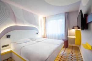 a bedroom with a large white bed and a window at Prize by Radisson, Osnabruck in Osnabrück