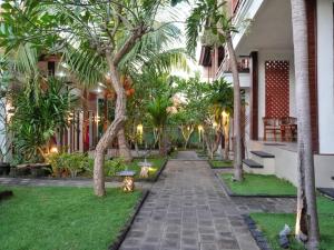a courtyard with palm trees and a cat sitting on the grass at Lembongan Cempaka Villa & Restaurant in Nusa Lembongan