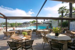 a restaurant with tables and chairs and a swimming pool at Le Ali Del Frassino in Peschiera del Garda