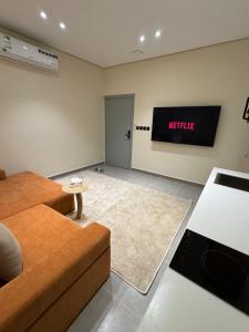 a living room with a couch and a television on the wall at Luxury studio in Al-ʿUla
