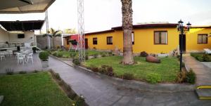 a yellow house with a courtyard with a palm tree at Casa Grau Chincha in Chincha